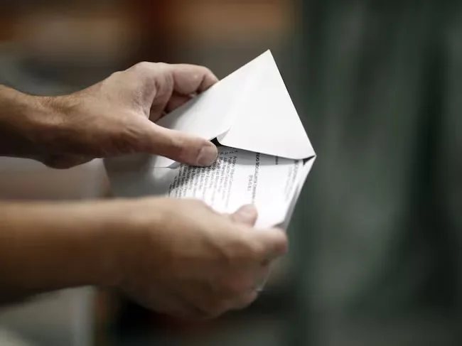 Una persona abre un sobre con documentación electoral